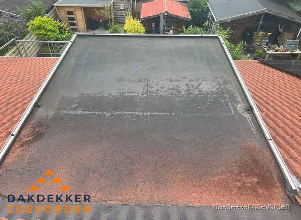 Verouderd plat dak met slijtage tussen schuine daken in Coevorden Verouderd plat dak met slijtage tussen schuine daken in Coevorden